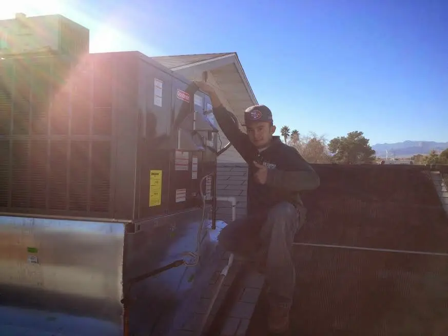 HVAC technician performing Boiler Repair on a rooftop unit in Le Mars