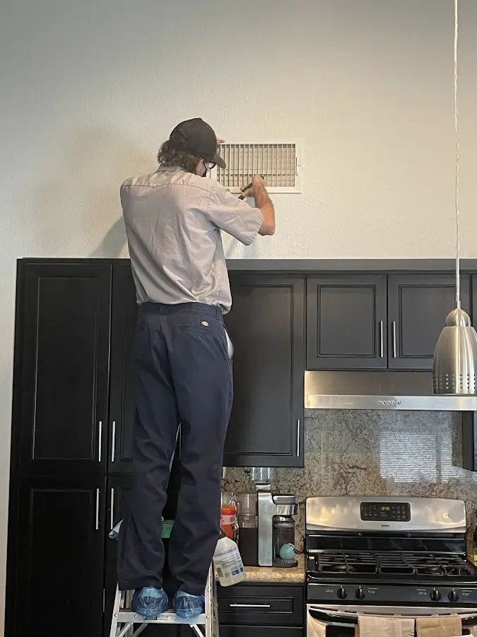 Technician inspecting an air vent during HVAC service in Le Mars